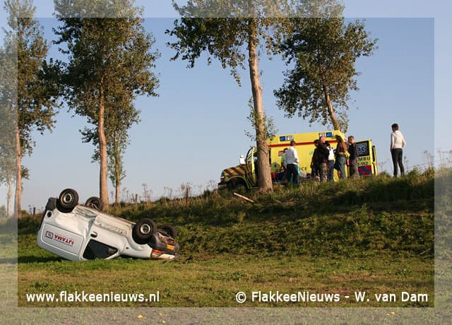 Auto op z'n kop naast de dijk