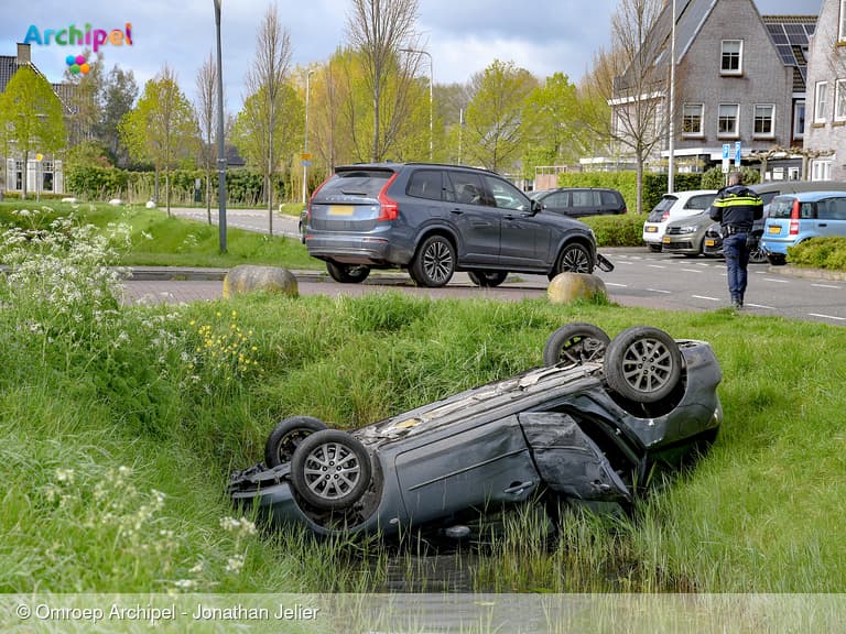 Auto ondersteboven in sloot bij kruising in woonwijk