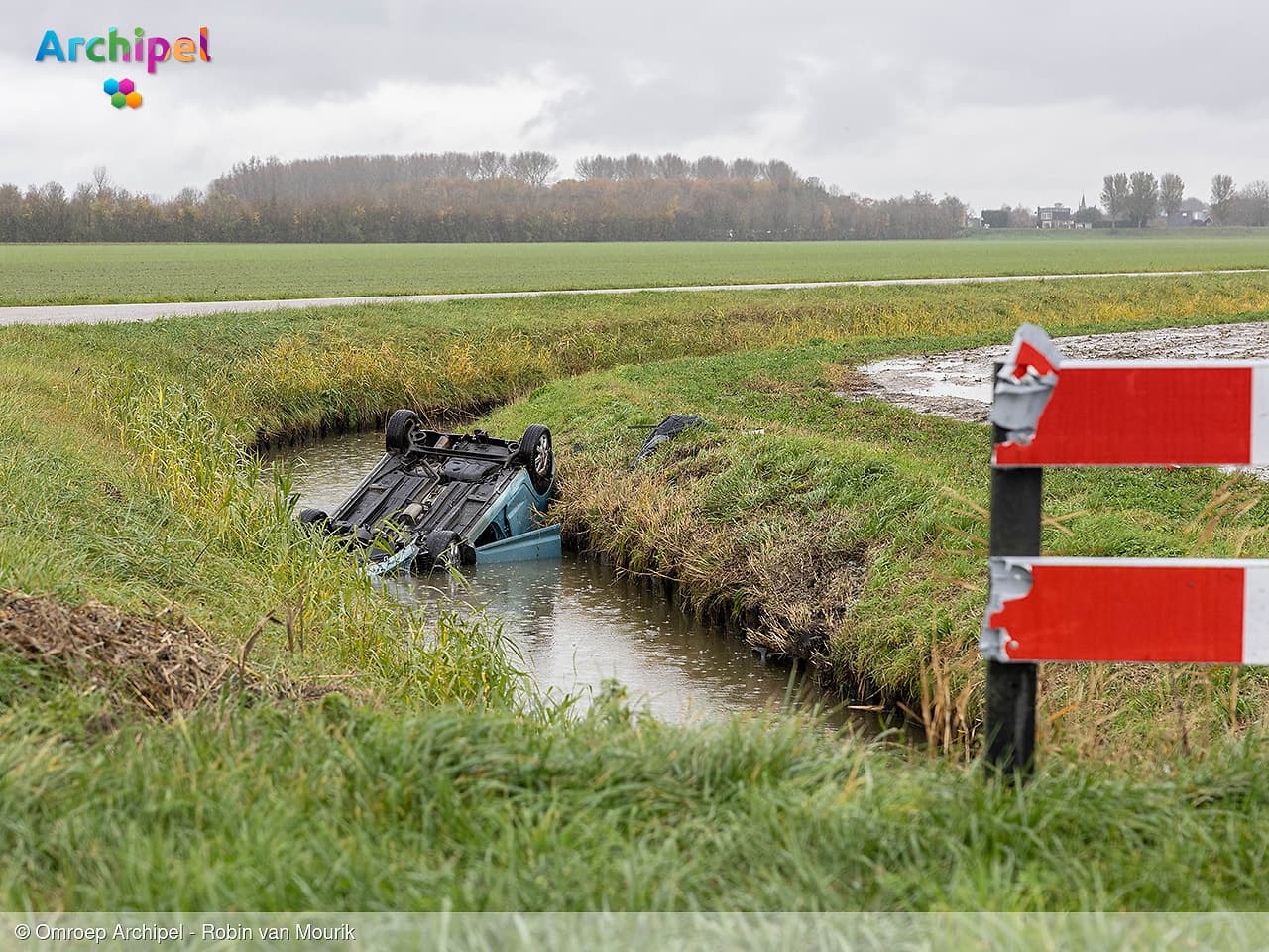 Auto botst tegen hek en belandt ondersteboven in sloot