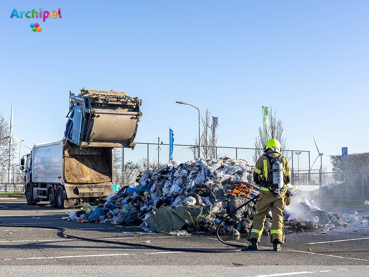 Vuilniswagen leegt afval op parkeerplaats wegens brand