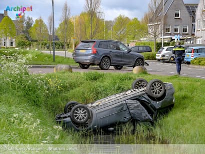 Auto ondersteboven in sloot bij kruising in woonwijk