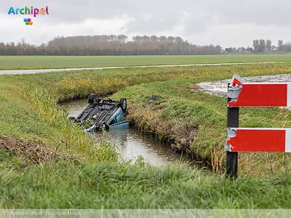 Auto botst tegen hek en belandt ondersteboven in sloot