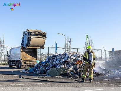 Vuilniswagen leegt afval op parkeerplaats wegens brand