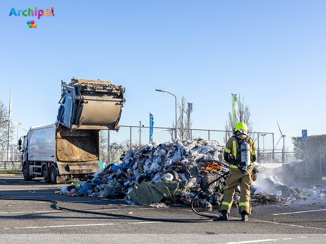 Vuilniswagen leegt afval op parkeerplaats wegens brand