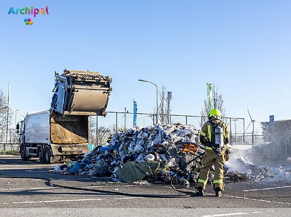 Vuilniswagen leegt afval op parkeerplaats wegens brand